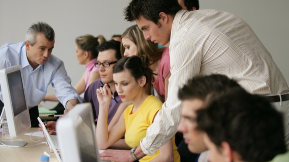 Studenten Mehrere Studenten helfen sich gegenseitig am Computer